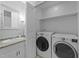 Bright laundry area features a side-by-side washer and dryer, and a vanity area with granite countertop and decorative mirror at 801 Silver Leaf Pl, Raleigh, NC 27609