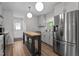 Modern kitchen with stainless steel appliances, light wood flooring, white cabinets, and an island, well-lit by pendant lighting at 8333 Bellingham Cir, Raleigh, NC 27615