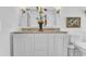 Bright bathroom featuring double sink vanity with decorative mirror, sconces, and white cabinets at 8721 Attingham Dr, Raleigh, NC 27615