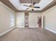 A main bedroom with neutral walls, a tray ceiling with fan, lots of windows, and carpet flooring at 1008 Maduro Ct, Zebulon, NC 27597