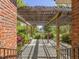 Covered patio with a wooden pergola, brick details, and lush landscaping in the backyard at 1008 Maduro Ct, Zebulon, NC 27597
