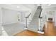Bright foyer showcasing hardwood floors, staircase with black railings, and living area with soft gray carpet at 102 Cockleshell Ct, Cary, NC 27513