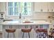 Bright kitchen features white cabinets, island with seating, stainless appliances and view to the backyard at 107 Hillcrest Ave # C And D, Carrboro, NC 27510