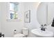 Bright half bath with modern fixtures including pedestal sink, round mirror, modern fixtures, and a window at 107 Hillcrest Ave # C And D, Carrboro, NC 27510