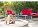 Cozy backyard with stone fire pit, seating with red cushions, and a small table, perfect for outdoor entertaining at 1109 Huntington Ave, Durham, NC 27707