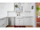 A well-lit kitchen showcasing a stainless steel dishwasher, a farmhouse sink, and white cabinets at 1109 Huntington Ave, Durham, NC 27707