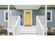 Inviting front porch with bright yellow door, white railings, and a black and white striped welcome mat at 111 Dunstan Ave, Durham, NC 27707