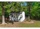 Well-maintained storage shed with white paint and green trim, surrounded by mature trees at 1120 Shetland Ct, Raleigh, NC 27609