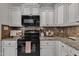 Kitchen features granite counters, white cabinets, and black appliances at 119 Wolf Creek Dr, Wendell, NC 27591