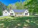 Lush backyard view of a charming home, featuring mature trees and manicured lawn at 1208 Goodwin Rd, Apex, NC 27523