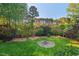 Lush backyard boasts a well-manicured lawn, mature trees, and fire pit for relaxation and outdoor gatherings at 1216 Caribou Xing, Durham, NC 27713