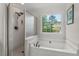 Bright bathroom featuring a soaking tub, shower, and a large window offering ample natural light at 1216 Caribou Xing, Durham, NC 27713