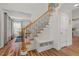 Bright foyer with wood floors and staircase with bench and wrought iron spindles at 1216 Caribou Xing, Durham, NC 27713