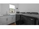 A modern laundry room with a window, gray cabinets, sink, Samsung washer, and dryer at 127 Sanderway Dr, Chapel Hill, NC 27516