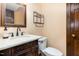 Elegant half-bathroom with a decorative mirror, vanity with marble countertop, and a toilet at 1400 Rainwood Ln, Raleigh, NC 27615