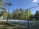Fenced tennis court on a sunny day with trees surrounding the court, promoting healthy living at 1425 Bascomb Dr, Raleigh, NC 27614
