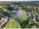 Aerial view of a scenic community with a golf course, lake, clubhouse, and well-maintained homes at 145 Ryder Cup Cir, Raleigh, NC 27603