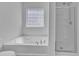 Bright bathroom with a soaking tub with shower head and glass enclosure with a patterned window at 145 Ryder Cup Cir, Raleigh, NC 27603