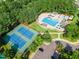 Aerial view of blue and green tennis courts next to a community pool surrounded by a lush, green landscape at 145 Ryder Cup Cir, Raleigh, NC 27603