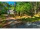 A home's exterior surrounded by lush woods, featuring a long driveway and convenient mailbox at 15 Pine Ridge, Pittsboro, NC 27312