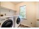 Bright laundry room with modern washer and dryer units and a window with green outdoor view at 15 Pine Ridge, Pittsboro, NC 27312