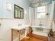 Bathroom with white wainscoting, pedestal sink, soaking tub, and a window for natural light at 1811 Park Dr, Raleigh, NC 27605