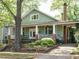 Charming green home with a inviting front porch framed by lush landscaping and mature trees at 1811 Park Dr, Raleigh, NC 27605