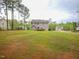 Expansive green backyard with mature trees and view of the rear of the home at 198 Shadowbark Dr, Garner, NC 27529