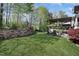 Landscaped backyard featuring a stone wall, wooden deck with pergola, and outdoor seating area, perfect for relaxation at 216 Bella Rose Dr, Chapel Hill, NC 27517