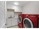 Functional laundry room with sink, white cabinets, and modern red appliances at 216 Bella Rose Dr, Chapel Hill, NC 27517