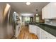 Open kitchen with wood floors, white cabinets, modern appliances, and eat-in dining area at 216 Harvester Dr, Holly Springs, NC 27540