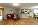 Spacious living room featuring hardwood floors, a red sofa, and open access to the kitchen and dining area at 216 Harvester Dr, Holly Springs, NC 27540