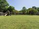 Expansive backyard with lush green grass, swing set, and a playhouse at 2213 Ravens Creek Ct, Raleigh, NC 27603