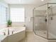 Bright bathroom featuring a soaking tub, glass enclosed shower with tiled walls, and decorative window at 2213 Ravens Creek Ct, Raleigh, NC 27603