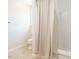 Neutral colored bathroom with toilet and combination tub and shower with patterned curtain at 2213 Ravens Creek Ct, Raleigh, NC 27603