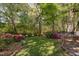 Beautiful backyard featuring a lush lawn, mature trees, and colorful flowering bushes at 2221 Dungiven Ct, Garner, NC 27529