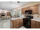Open kitchen design with black appliances, wooden cabinets, and dining area at 2221 Dungiven Ct, Garner, NC 27529