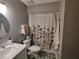 Bathroom with unique flower curtain, round mirror and white sink on marble counter at 26 Stonewall Way, Durham, NC 27704