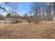 View of the home's expansive and unkept backyard featuring dormant lawn and trees at 2670 Turner Rd, Mebane, NC 27302