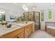 Bathroom featuring double sinks, a glass shower, and natural light from large windows at 2900 Old Trafford Way, Raleigh, NC 27606