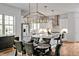 An elegant dining room with a glass table, leather chairs, and modern chandelier adjoins a bright, white kitchen at 30 Mist Wood Ct, Pittsboro, NC 27312