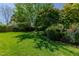 Lush backyard features mature trees, green grass, and privacy, creating a tranquil outdoor oasis at 308 Grove Hall Ln, Mebane, NC 27302