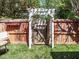 Charming backyard gate in a wooden fence with a decorative pergola and flowering trees at 3125 Morningside Dr, Raleigh, NC 27607