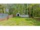 Green backyard featuring a pair of weathered, vintage sheds and surrounded by a wooden fence and lush trees at 322 W Hill N Ave, Hillsborough, NC 27278