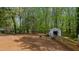 Expansive backyard featuring dirt terrain and large shed, surrounded by lush trees and greenery at 322 W Hill N Ave, Hillsborough, NC 27278