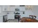 A classic-style kitchen with white cabinets, stainless appliances, mosaic backsplash, and a charming breakfast table setup at 322 W Hill N Ave, Hillsborough, NC 27278