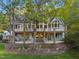 Back of the home featuring a stone foundation, a deck, a patio and beautiful landscaping under a clear sky at 32430 Archdale, Chapel Hill, NC 27517