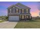 Traditional two-story home boasts stone accents, a two car garage, and manicured front lawn at 411 Lawton Dr, Haw River, NC 27258
