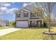 Attractive two-story home featuring a two-car garage, gray siding, and a manicured lawn under a partly cloudy sky at 411 Lawton Dr, Haw River, NC 27258