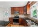 Kitchen with updated appliances, wood cabinetry, granite counters, and stainless steel double sink at 4902 Brookhaven Dr, Raleigh, NC 27612